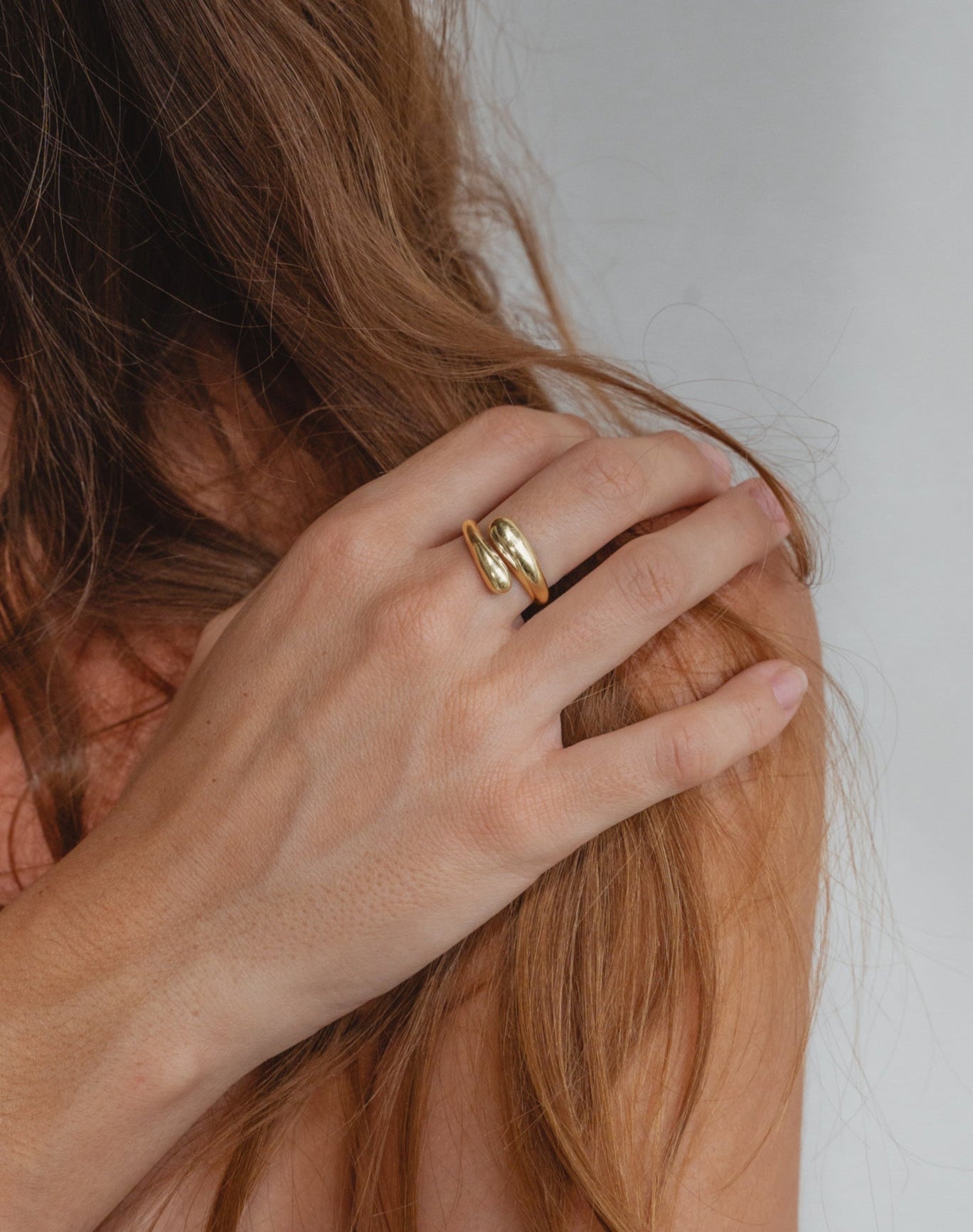 goldener Tropfen Ring in Schlangen Form auf gebräunter Haut. Das Model trägt auffälligen Gold Schmuck aus Bali