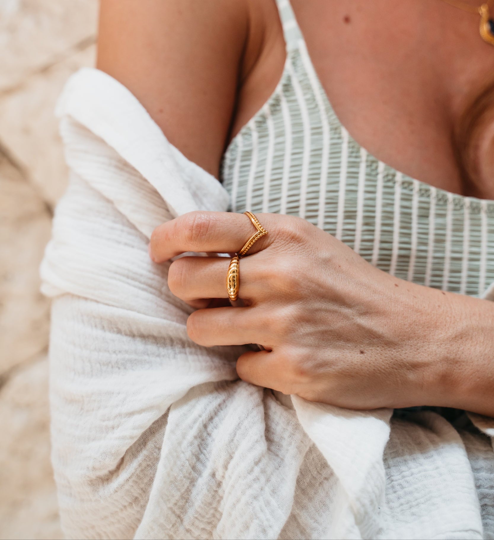 Goldener V Ring im Boho Style mit goldenem Croissant Ring an weiblichem Model. Sie trägt Schmuck aus Bali kombiniert mit weißer Musselin Bluse und gestreiftem Top.