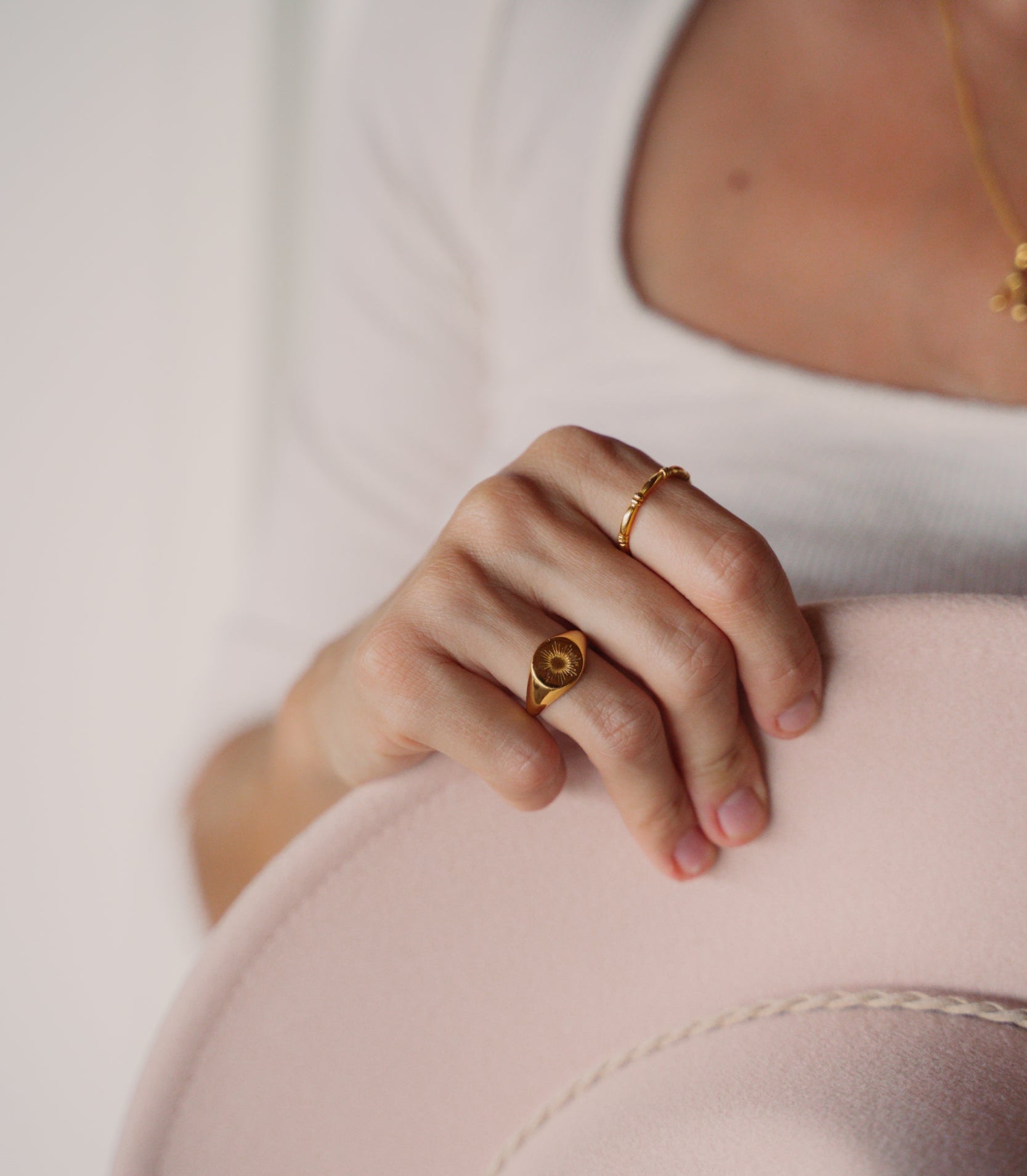 model trägt goldenen Ring und einen goldenen breiten Statement Ring, kombiniert mit beigem Hut und dunklen Haaren. Hati Ring von VERLAN