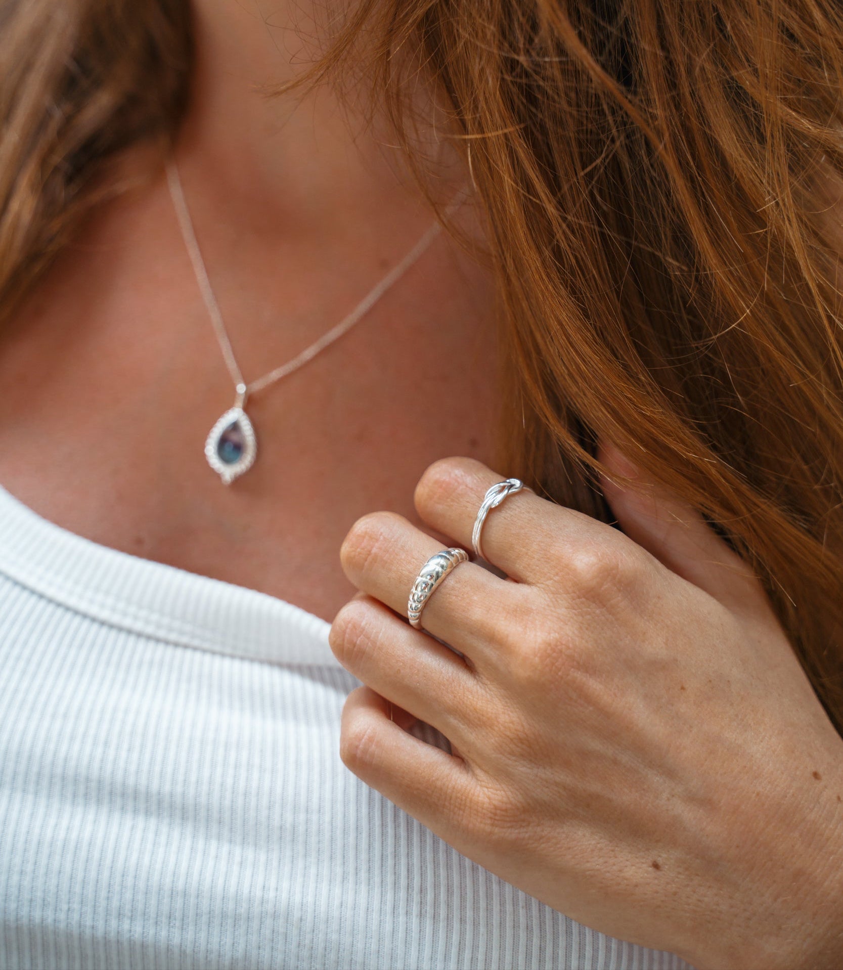 Silber ringe aus Bali an weiblichem Model. Croissant Ring und Knoten Ring aus Echtsilber, die wasserfest sind. Das Model trägt ein helles T Shirt und hat lange braune Haare.